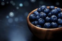 Fresh blueberries in wooden bowl on dark background with bokeh lights for healthy eating and nutrition concepts.