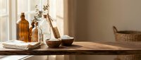 Natural spa wellness setup with amber bottles, wooden bowls and eucalyptus branches on rustic table for aromatherapy and organic skincare treatments.