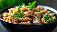 Delicious pasta with roasted mushrooms and fresh herbs in black bowl, perfect for restaurant menus, food blogs, and culinary marketing materials.