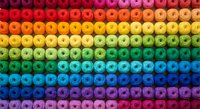 Colorful rainbow gradient of round emoji faces arranged in rows creating vibrant spectrum pattern from red to purple for creative design projects.