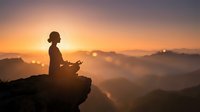 Woman meditating in lotus pose on mountain peak at sunrise with golden light and misty valleys creating peaceful spiritual atmosphere for wellness content.