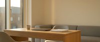 Minimalist wooden desk with laptop and coffee cup in modern home office workspace with natural lighting and neutral beige walls for productivity and remote work.