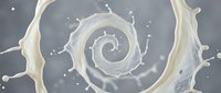 Creamy white liquid swirl with splashing droplets and spiral motion against gray background, suitable for cosmetics, dairy, or beverage marketing materials.