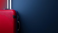 Red hard shell suitcase on dark blue background with copy space. Modern minimalist travel luggage against gradient backdrop for vacation concept.
