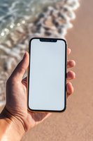 Hand holding modern smartphone with blank white screen against blurred background with bokeh lights. Mock up for app or website presentation.