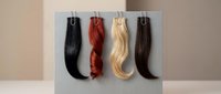 Hair extension samples in various colors including black, auburn, blonde and brown hanging on display clips for beauty salon or wig shop showcase.