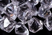 Clear quartz crystal chunks with sharp geometric faces and natural formations on black background, showing raw mineral structure and light reflections.