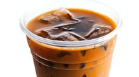 Refreshing iced coffee drink with dark coffee cubes in clear plastic cup on white background, cold brew beverage isolated for cafe menu and advertising.