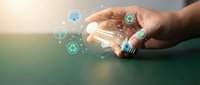 Hand holding a glowing light bulb with green energy icons, symbolizing renewable power, eco innovation, and sustainable technology concepts.