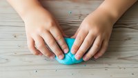Child hands protecting blue heart shape on wooden background symbolizing care, love, protection and family values concept.