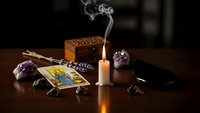 Mystical tarot reading setup with burning candle, smoke, crystals and cards on wooden table creating atmospheric fortune telling scene for spiritual guidance.