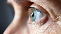Close-up macro shot of human blue-green eye with detailed iris patterns and eyelashes. Medical anatomy concept for vision care and ophthalmology studies.