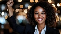 Successful African American businesswoman celebrating achievement with raised fist against bokeh lights background. Corporate success and empowerment concept.