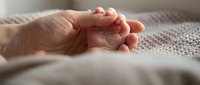 Newborn baby tiny hand resting in adult palm, soft light, tender family moment capturing love and generational bond between parent and child.