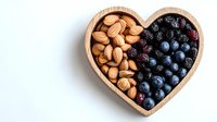 Fresh blueberries, blackberries and almonds in wooden heart shaped bowl on white background, healthy snack concept for Valentine's day or romantic dining.
