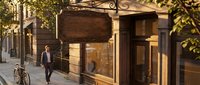 Elegant storefront with warm lighting and ornate awning on charming city street during golden hour, showcasing retail architecture and urban commercial space.