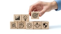 Business professional hand selecting wooden cube with target icon from row of strategy blocks representing goal achievement and corporate planning.