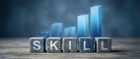 Wooden letter blocks spelling SKILL with glowing blue bar chart in background representing professional development and career growth concept.