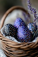 Decorated Easter eggs with dotted patterns in deep blue and purple tones nestled in wicker basket with lavender sprigs and lace doily. Perfect for spring celebrations.