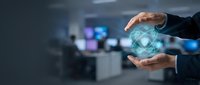 Businessman holding glowing atom symbol between hands in modern office environment, representing science, technology, innovation, and nuclear energy research for corporate presentations.