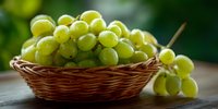 Fresh green grapes in wicker basket on wooden table with blurred natural background, perfect for food blogs, wine marketing, and healthy eating content.