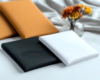 Minimalist leather wallets in black, white and tan displayed on white fabric with autumn flowers in glass vase, modern accessories photography for retail.
