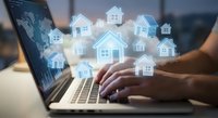 Digital real estate concept with glowing house icons floating above laptop keyboard. Online property search and virtual home buying technology.