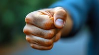 Close up view of clenched fist showing aggression and strength against blurred green background, demonstrating power, anger and confrontation concept.