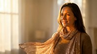 Young Hispanic woman in cozy sweater enjoying warm sunlight streaming through window at home, creating peaceful morning atmosphere for lifestyle content.