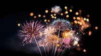 Spectacular fireworks display lighting up night sky with pink, white and golden bursts creating magical atmosphere for celebration and festive events.