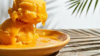 Crispy golden fried onion rings stacked on wooden plate with palm leaf shadow, ready for food styling, restaurant menus, culinary blogs and snack packaging designs.