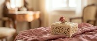 Elegant wooden jewelry box with rose decoration on luxurious silk bedding in warm sunlit bedroom interior for romantic home decor and storage solutions.
