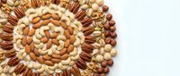 Assorted nuts arranged in decorative spiral pattern on white background including almonds, walnuts, cashews, hazelnuts and pistachios for healthy snacking.