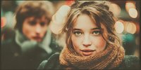 Young blonde woman in knitted scarf with warm bokeh lights background, cozy winter evening atmosphere, romantic couple scene for lifestyle content.
