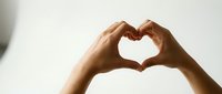 Two hands forming a heart shape against a light background, symbolizing love, care, and connection for Valentine's Day or wellness concepts.