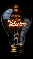 Vintage light bulb with glowing Valentine text inside, illuminated filament against dark background creating romantic atmosphere.