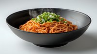 Steaming hot noodles in spicy sauce topped with fresh chopped green onions served in modern black ceramic bowl on light background. Perfect for menu design.