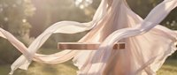 Flowing pastel pink fabric billowing in sunlit garden with elegant rose gold metallic bar, soft bokeh background, dreamy romantic atmosphere.