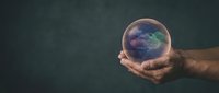 Hands holding glowing crystal ball with colorful cosmic nebula inside against dark textured background for fortune telling and mystical concepts.