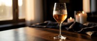Elegant wine glass filled with golden white wine on wooden table with warm candlelight creating romantic dining atmosphere for restaurant menu design.
