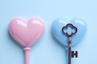 Pink heart lollipop and vintage key with heart-shaped handle on blue background, romantic concept for valentines day and love relationships.