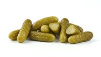 Pickled gherkins and sliced cucumber pieces isolated on white background, ready for food packaging, recipe blogs, grocery retail, and culinary design projects.