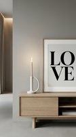 Minimalist Scandinavian living room with wooden sideboard, lit candle in white holder, and framed love typography art print on gray wall.