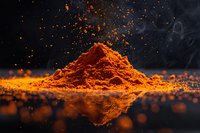 Orange spice powder heap with floating particles and reflection on dark background, dramatic lighting creates mystical culinary atmosphere for food photography.