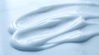 Smooth white gel or cream texture with glossy swirls on light background, suitable for skincare, cosmetics, and beauty product packaging design.