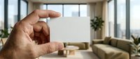 Hand holding blank white business card in modern office interior with city view and contemporary furniture for corporate branding mockup.