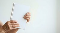 Senior male hands holding blank white card and pen against neutral background for messaging and communication concepts.