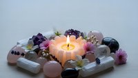 Healing crystals and gemstones arranged around glowing candle for meditation, spiritual wellness, chakra balancing and holistic therapy practices.