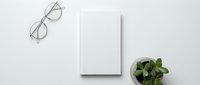 Minimalist workspace flat lay with blank white notebook, eyeglasses and green plant on clean white background for business branding and design projects.