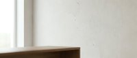 Minimalist interior corner with wooden shelf edge and white wall with natural light from window.